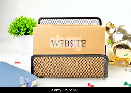 Une configuration d'espace de travail comprenant un porte-carte affichant des cartes de site Web, de la papeterie colorée, une plante en pot et une tirelire décorative, illustrant un o Banque D'Images