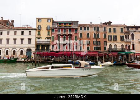 VENISE, ITALIE - 24 OCTOBRE 2024 : un bateau à moteur Taxi voyage le long d'un canal à Venise, Italie, en passant devant un bâtiment historique. Paysage urbain vénitien classique Banque D'Images