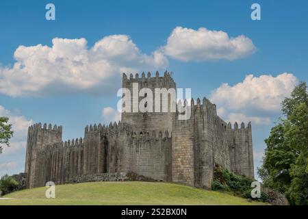 Guimarães château Portugal fait de blocs de granit, journée ensoleillée avec ciel bleu et nuages. Banque D'Images