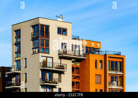 Immeuble résidentiel moderne à plusieurs étages avec façade vibrante, grands balcons et vue panoramique urbaine sous ciel bleu clair Banque D'Images