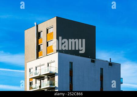 Immeuble résidentiel moderne à plusieurs étages avec façade vibrante, grands balcons et vue panoramique urbaine sous ciel bleu clair Banque D'Images