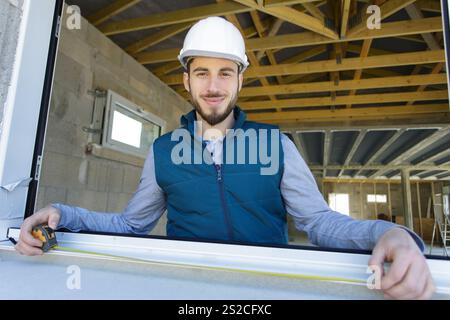 un constructeur mâle mesure une fenêtre Banque D'Images