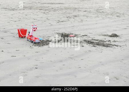 Gros plan d'un jouet en plastique moteur à incendie, seau, bêche et château de sable sur une plage de sable, Tofino, île de Vancouver, Colombie-Britannique, Canada Banque D'Images