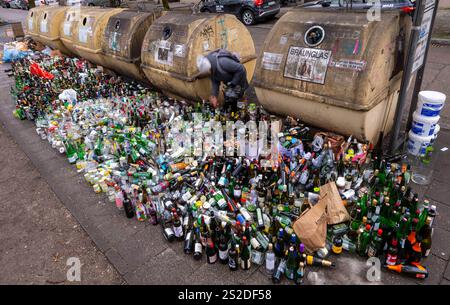 Munich, Allemagne. 07 janvier 2025. Des milliers de bouteilles et de bocaux en verre se dressent sur le trottoir devant des conteneurs de collecte surchargés au Postwiese dans le district de Haidhausen. Crédit : Peter Kneffel/dpa/Alamy Live News Banque D'Images