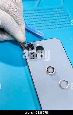 Technicien enlevant le verre de protection de la caméra d'un téléphone Banque D'Images