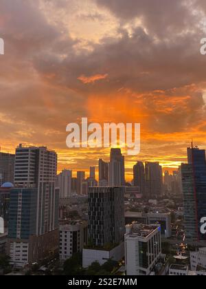 Coucher de soleil orange éclatant sur les gratte-ciel de Jakarta avec des nuages spectaculaires créant un paysage urbain époustouflant Banque D'Images