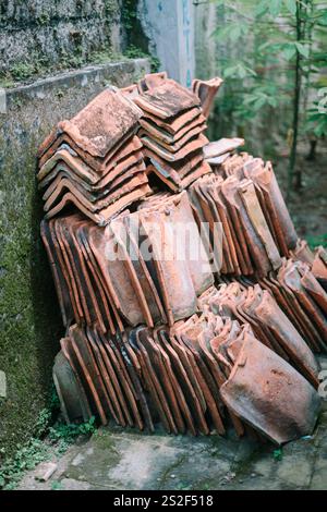 Tuiles de toit en argile soigneusement disposées sur le sol, prêtes à être installées, mettant en valeur les matériaux de construction traditionnels pour la toiture Banque D'Images