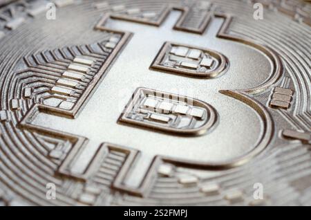 Gros plan d'un bitcoin physique avec une surface de relief brillante en chocolat. Image abstraite de la monnaie crypto sous une forme comestible Banque D'Images