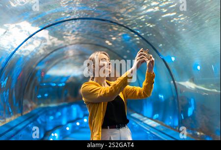 Une femme dans un tunnel sous-marin avec des créatures marines. Banque D'Images