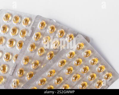 Gros plan des capsules d'huile de poisson dans des emballages sous blister sur la surface blanche. concepts de santé et de nutrition. Capsule jaune Blister, capsules d'huile de poisson Omega 3, jaune Banque D'Images