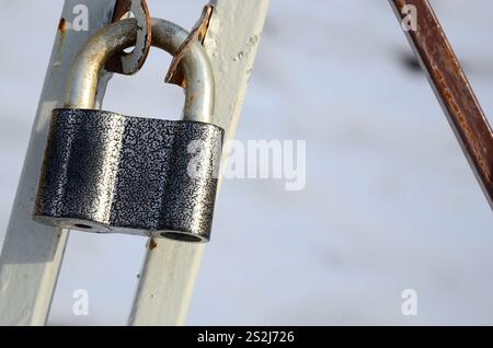 Un grand cadenas gris est suspendu à une porte en métal Banque D'Images