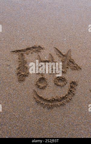 Message de remerciement abrégé avec visage souriant dessiné dans le sable Banque D'Images