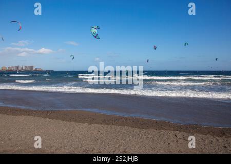 Une complétion de kite surfeurs à la plage El Medano à Tenerife dans une journée venteuse avec un ciel bleu clair. Banque D'Images
