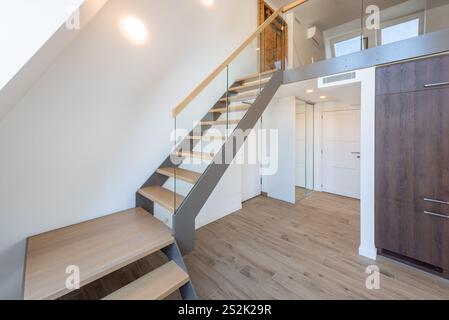 Escaliers et balustrade modernes en bois. À l'étage. Murs blancs, lumière LED. Intérieur de la maison.. Appartement de style loft. Porte en bois blanc. Intérieur de la maison Banque D'Images