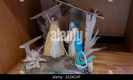 Une scène de nativité artisanale faite de matériaux de paille naturelle, mettant en vedette Marie, Joseph et le bébé Jésus dans une simple écurie en bois. Un jour férié serein d Banque D'Images