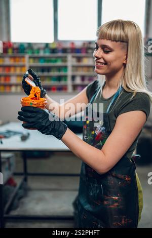 Portrait de technicien graphique féminin professionnel debout à l'atelier d'impression avec la boîte d'encre dans les mains et le mélangeant. Femme souriante magasin d'imprimerie Wor Banque D'Images