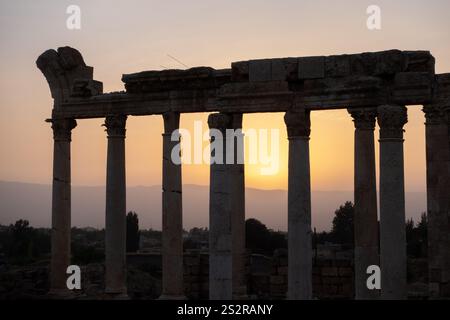 Le beau soleil se couche lentement derrière les colonnes impressionnantes d'un bâtiment ancien, projetant une vue imprenable Banque D'Images