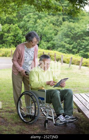 Couple de personnes âgées regardant une tablette dans un parc Banque D'Images