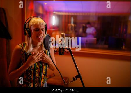 Portrait d'un artiste talentueux debout dans un studio d'enregistrement et chantant une chanson pendant une session d'enregistrement dans un studio. Un chanteur chante et solo Banque D'Images