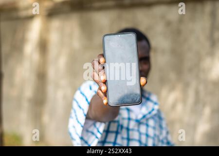 Recommandation. Portrait d'un homme noir afro-américain excité tenant un grand smartphone avec un écran blanc noir à la main, montrant près de la caméra. Gadget Banque D'Images