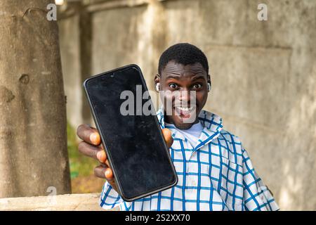 Recommandation. Portrait d'un homme noir afro-américain excité tenant un grand smartphone avec un écran blanc noir à la main, montrant près de la caméra. Gadget Banque D'Images