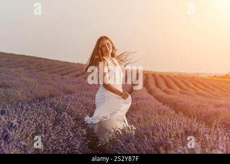 Lavender Fields femme Robe coucher de soleil : femme d'été joyeuse en robe blanche courant à travers les champs de lavande de Provence en fleurs au coucher du soleil. Banque D'Images