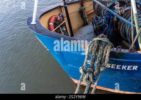 Proue de chalutier de pêche attachée par une corde de nylon au bord du quai de West Bay Harbour, Dorset. Peinture bleue avec le nom Sunseeker Banque D'Images