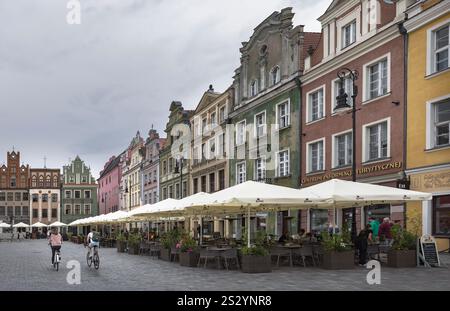 Les visiteurs se promènent sur la place du marché de Poznan, appréciant la culture des cafés au milieu de bâtiments historiques colorés, en Pologne Banque D'Images