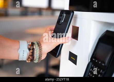 Girl utilise son smartphone pour scanner le code QR au terminal libre-service Banque D'Images