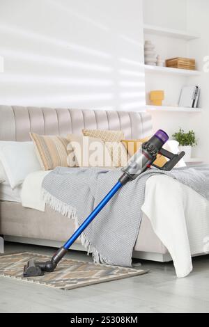 Un aspirateur sans fil reposant sur le lit à l'intérieur Banque D'Images