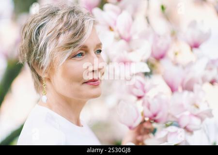Printemps gros plan portrait de belle femme de 55 - 60 ans posant avec un arbre magnolia Banque D'Images