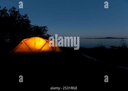 Camping au bord de l'océan dans une petite tente jaune. Banque D'Images