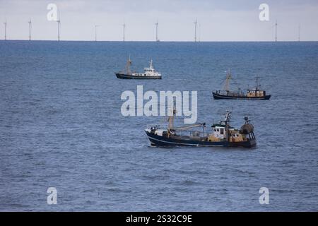 Trois bateaux de pêche devant un parc éolien en mer du Nord près d'Egmond aan Zee par temps clair Banque D'Images