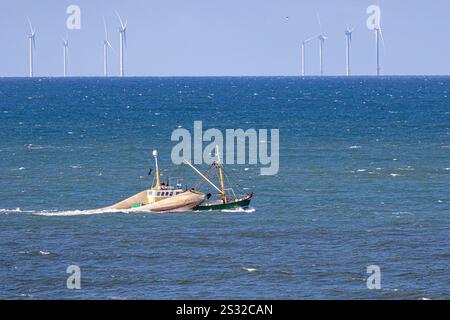 Un bateau de pêche avec des filets traînants levés devant un parc éolien en mer du Nord près d'Egmond aan Zee Banque D'Images