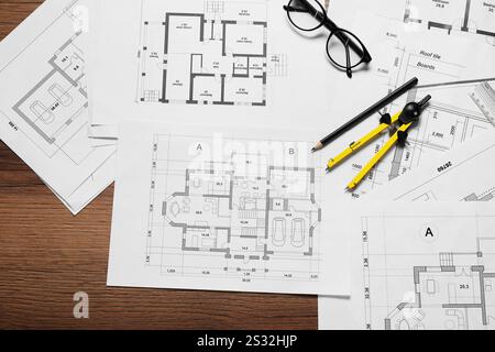 Différents dessins architecturaux, crayon, verres et séparateur sur table en bois, pose à plat Banque D'Images
