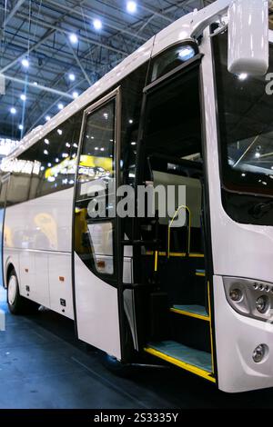 Un bus touristique blanc avec portes ouvertes est représenté. Des marches avec des bords jaunes et une vue partielle de l'intérieur du bus sont visibles. Banque D'Images