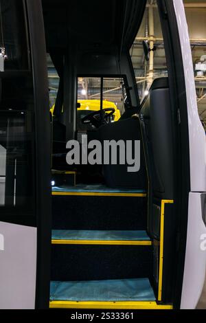 Un bus touristique blanc avec portes ouvertes est représenté. Des marches avec des bords jaunes et une vue partielle de l'intérieur du bus sont visibles. Banque D'Images