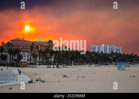 Los Angeles, États-Unis. 8 janvier 2025. Les gens marchent le long de la piste cyclable de Santa Monica un panache de fumée dérive au-dessus de Santa Monica alors que le feu Pacific Palisades brûle près de Los Angeles, en Californie. Des vents violents et des conditions sèches devraient intensifier les feux de forêt dans les Palisades du Pacifique. Crédit : Stu Gray/Alamy Live News. Banque D'Images