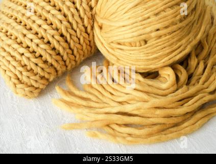 Tricot, écharpe et boule de fil jaune. Fibres synthétiques, motif tridimensionnel. Banque D'Images