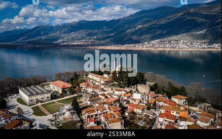Une vue aérienne panoramique met en valeur une petite ville pittoresque nichée à côté d'un lac serein, avec des montagnes majestueuses formant une toile de fond magnifique Banque D'Images
