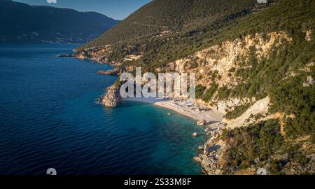 Une vue aérienne expansive met en valeur une plage pittoresque qui est magnifiquement entourée de montagnes majestueuses et d'arbres verdoyants tout autour Banque D'Images