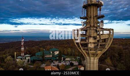 Cette image capture une vue aérienne montrant une tour remarquablement haute qui se dresse fièrement au milieu d'une forêt luxuriante et dense en toile de fond Banque D'Images