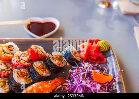 Assortiment de rouleaux de sushi avec gingembre mariné, wasabi et sauce soja servis sur un plateau en bois dans une présentation vibrante. Curaçao. Banque D'Images