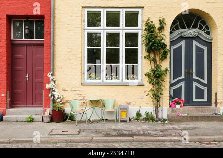 Deux vieilles portes d'entrée, rouge et bleue, avec un coin salon entre les deux Banque D'Images