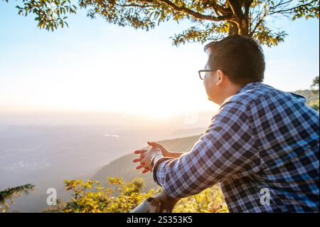 Vue latérale de l'homme voyageur heureux avec des lunettes debout regardant à la belle vue au point de vue, espace de copie Banque D'Images