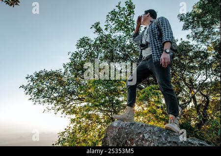 Vue arrière du jeune homme de randonnée asiatique debout au point de vue et regardant une belle vue avec heureux sur la montagne de pic et le soleil, espace de copie Banque D'Images