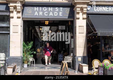 Cardiff Wales - 6 août 2024 : L'homme émerge de l'ombre en marchant à travers l'entrée de High Spécifications Arcade dans Castle Quarter. Banque D'Images