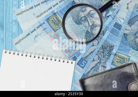 5 billets de hryvnias ukrainiens et loupe avec sac à main noir et bloc-notes. Concept de fausse monnaie. Recherchez des différences dans les détails sur l'argent Banque D'Images