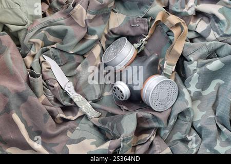 Les soldats stacker masque à gaz soviétique repose avec couteau sur des vestes de camouflage kaki vertes. Kit post-apocalypse Surviving items Banque D'Images