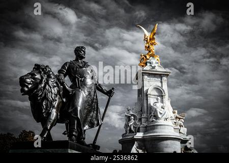 La statue d'un homme à côté d'un lion fait partie du mémorial de la Reine Victoria, sur la place devant le palais de Buckingham à Londres. Banque D'Images